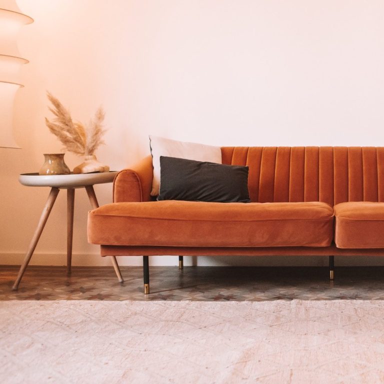Sala de terapia con un sofá naranja y una mesita al lado, creando un ambiente acogedor y tranquilo