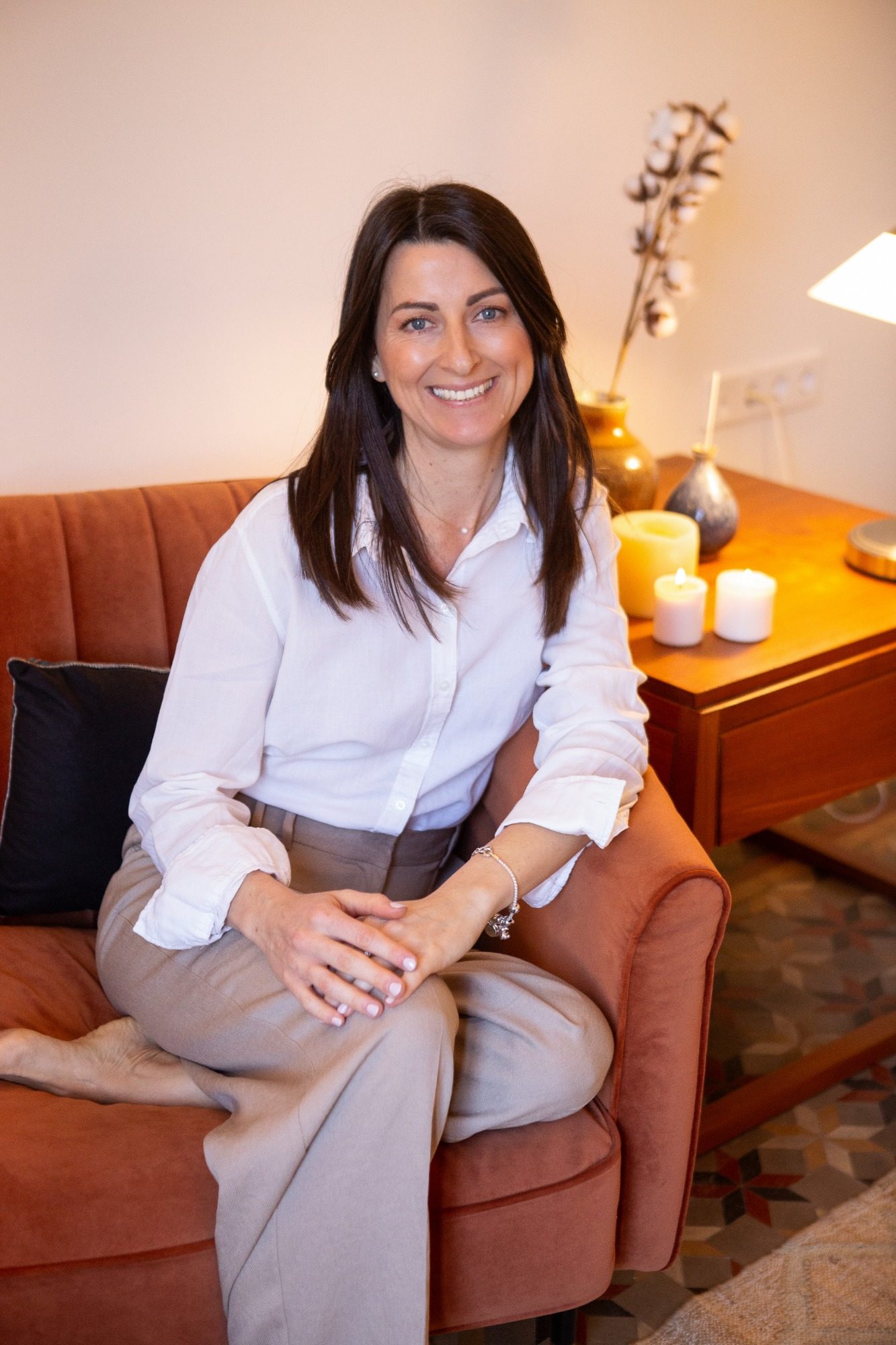 Mujer sonriendo, sentada en un sillón, con una expresión relajada y contenta