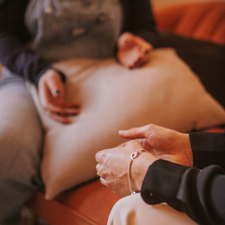 Primer plano de las manos de dos personas durante una sesión de terapia, capturando un momento de connexion y apoyo