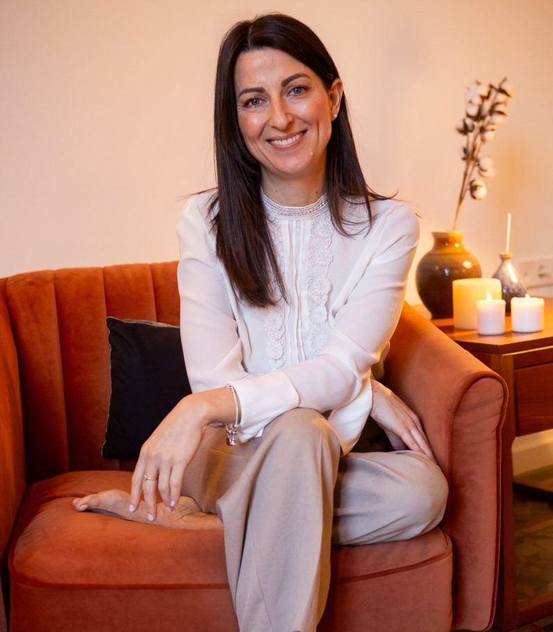 Mujer terapeuta sentada en un sillón, mirando con amabilidad y cercanía.